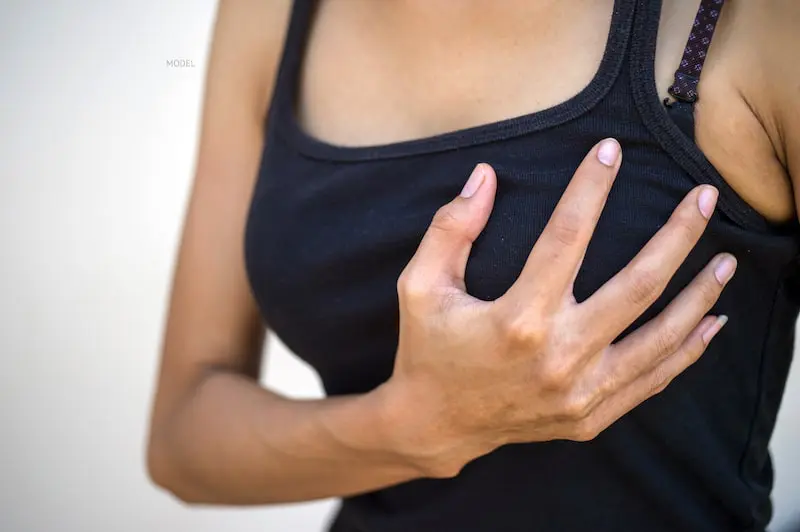 Woman cupping her breast with her hand over a black t-shirt