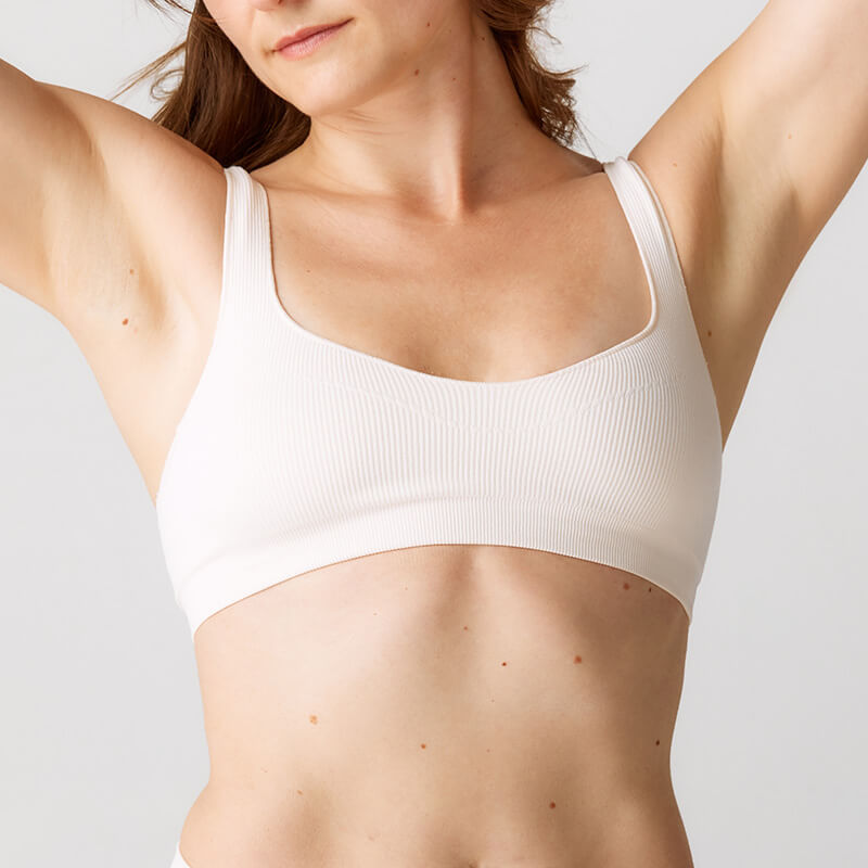 Woman in a white bra with her arms raised